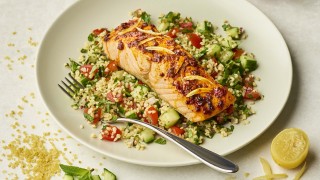 Harissa Salmon with Herby Tabbouleh served on a white plate with a lemon wedge on the side