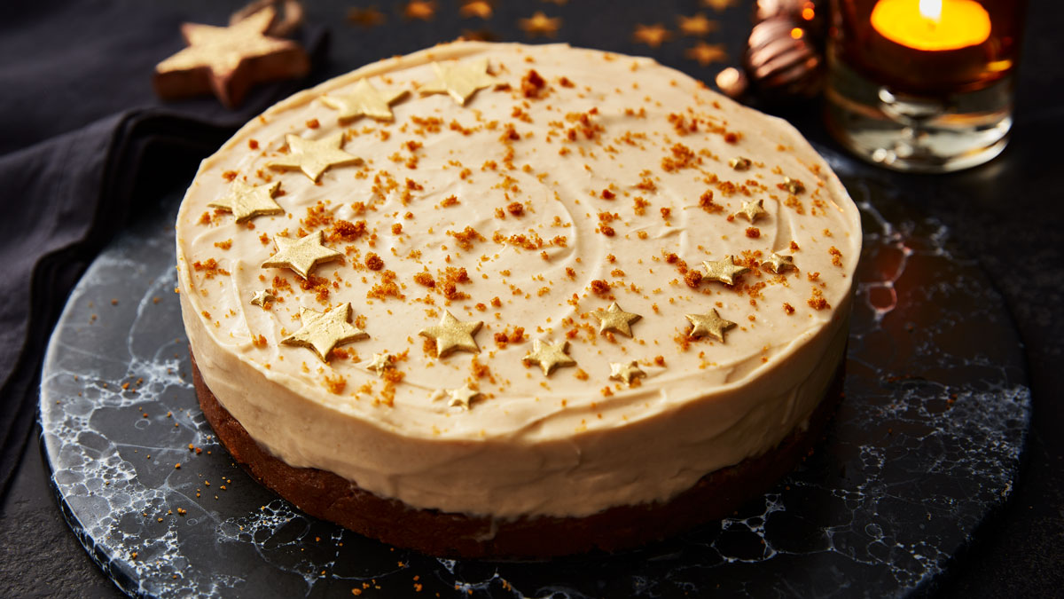 Gingerbread Cheesecake decorated with crumbs and gold stars served on a black marble plate