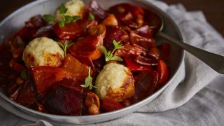 Hungarian Style Vegetable Stew with Potato Dumplings served in a white bowl on top of a grey table cloth