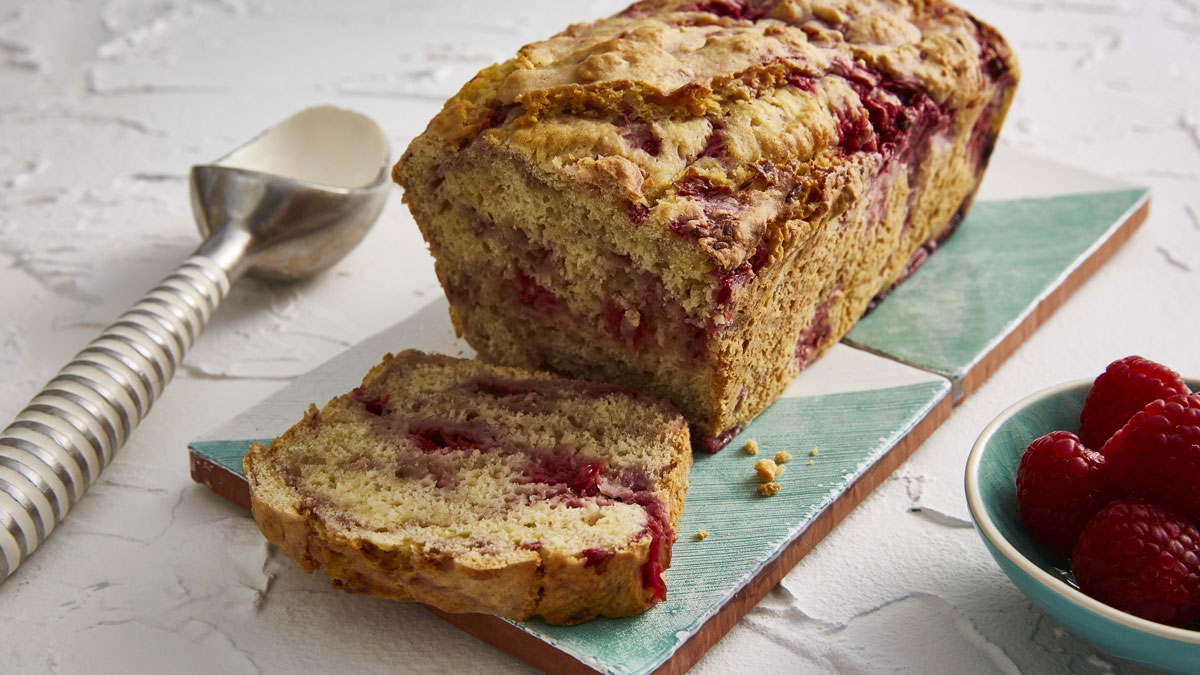 Ice Cream Bread served on two tiles next to an ice cram scoop and a bowl of raspberries