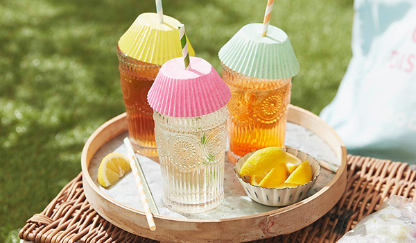 Summer drinks with cupcake cases over the top to keep insects out and a straw poking through.