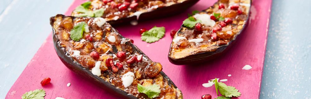 Jamaican Jerk Aubergine served on a pink wooden board and sprinkled with corriander