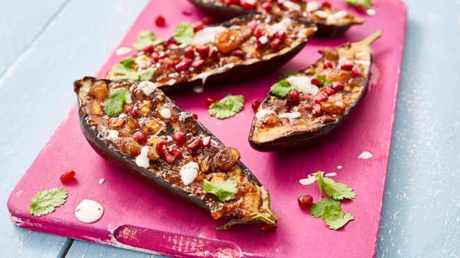 Jamaican Jerk Aubergine served on a pink wooden board and sprinkled with corriander