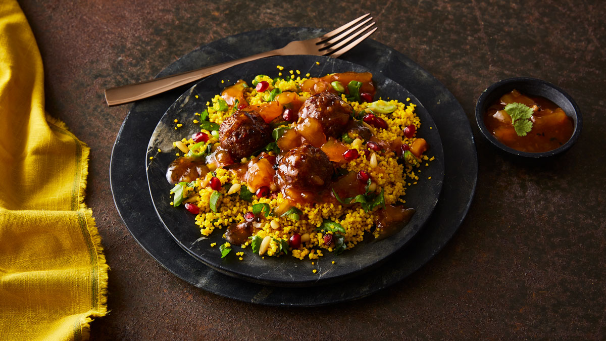 Lebanese Lamb Meatballs served on a bed of couscous on two black serving plates