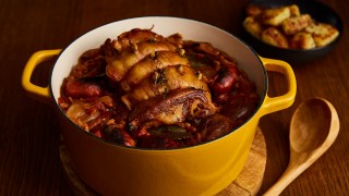 Pot Roasted Lamb with Chorizo served in a yellow casserole dish next to a wooden ladle