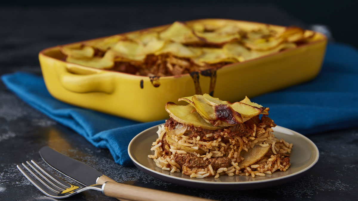 Lancashire Hotpot Biryani served in a yellow casserole dish with a portion served on a plate