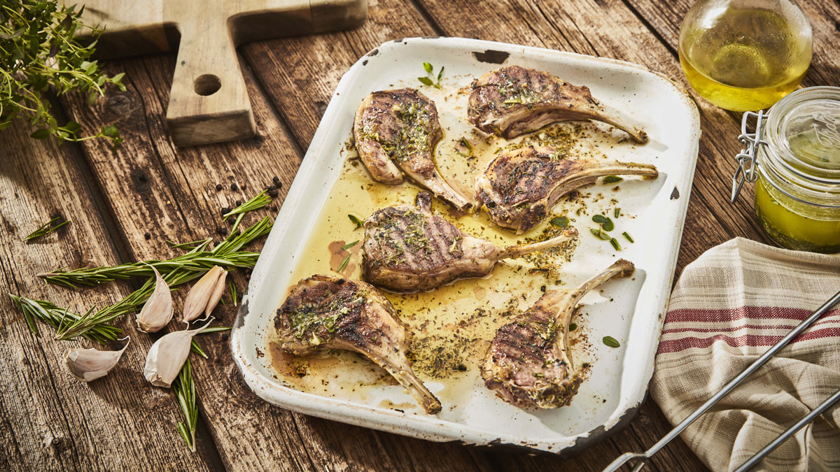 Super Easy Herb Marinated Lamb Chops served on a baking tray with sprigs on rosemary and olive oil