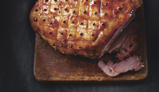 Marmalade and Mustard Glazed Christmas Ham carved and served on a wooden board