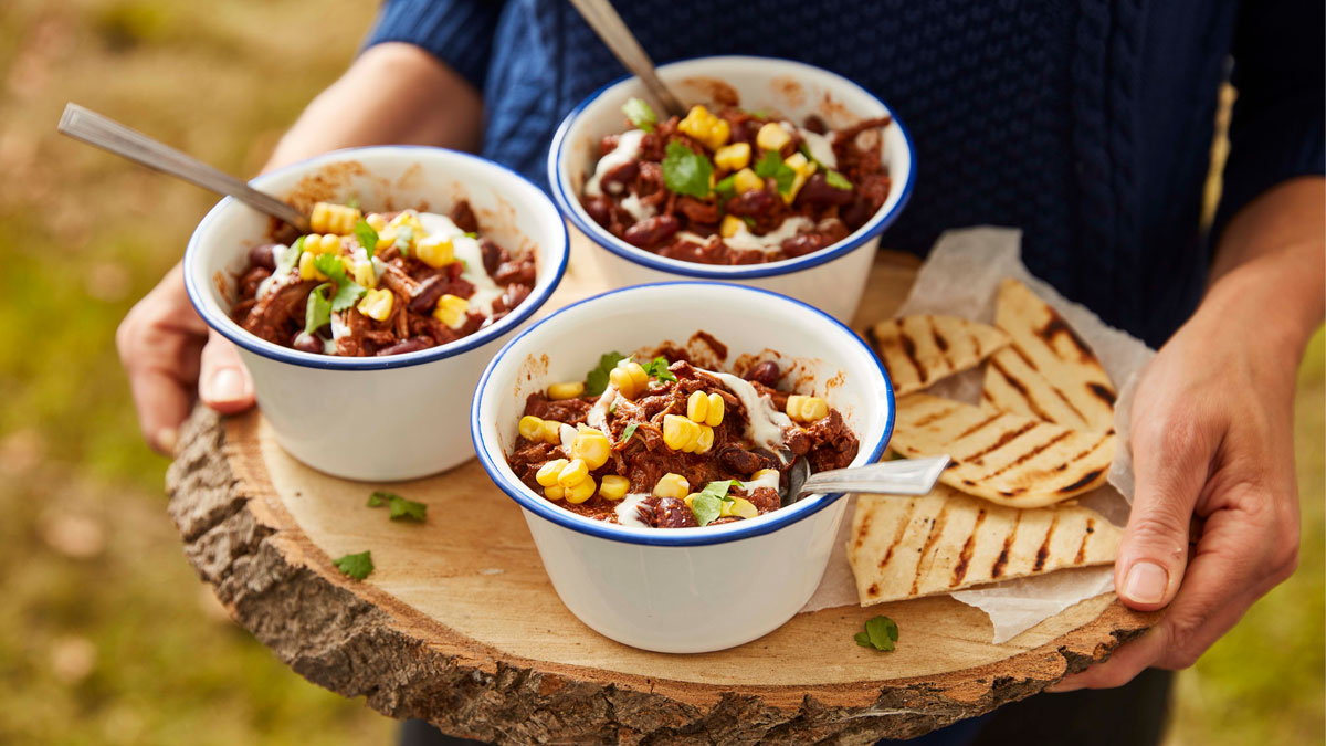 Mexican Mole Chilli served in dishes, on top of a wooden board with grilled tortillas