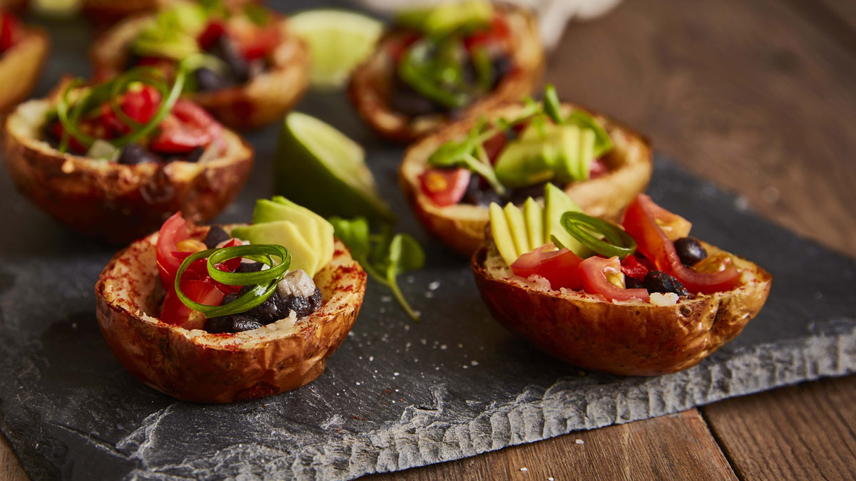 Mexican Style Mini Potato Skins (Vegan) served on a slate and topped with spring onions