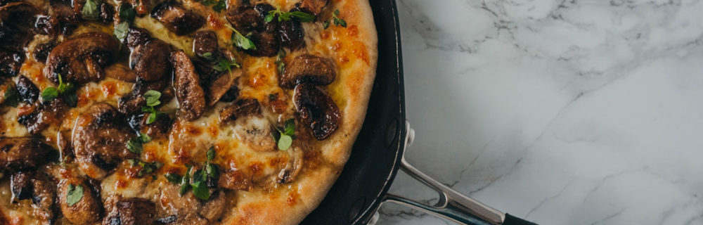 Northern Dough Co Creamy Mushroom and Garlic Pizza with Fresh herbs served on a black plate