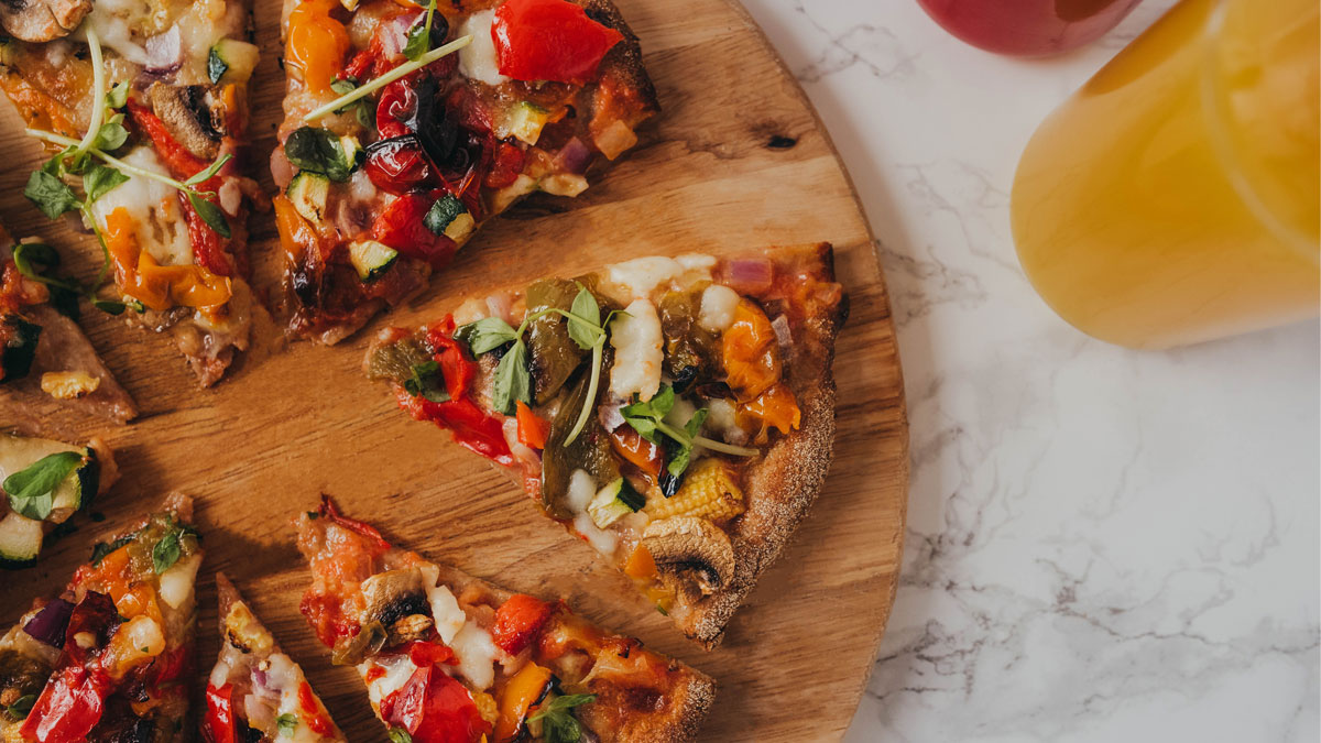 Veggie Packed Pizza with mozzarella, sliced and served on a wooden board