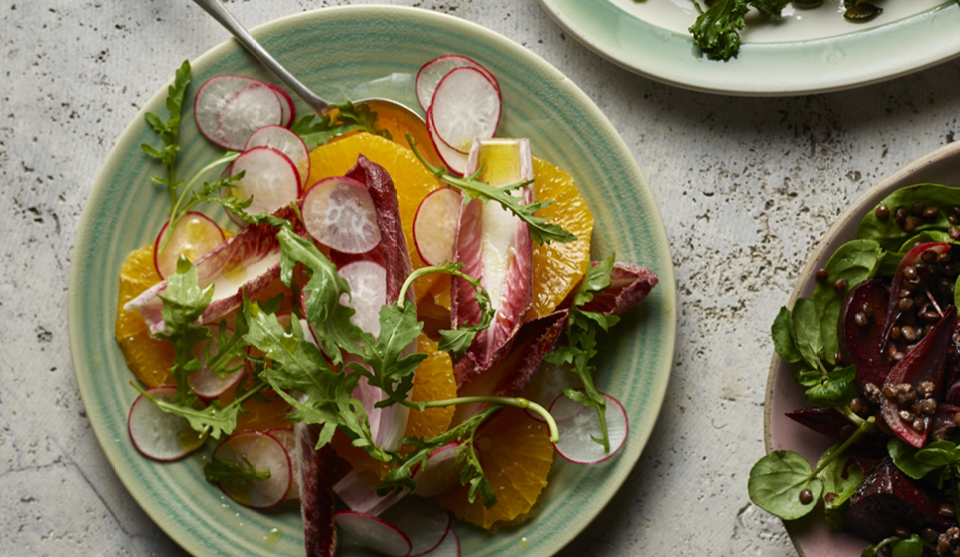 Orange, Red Chicory and Radish Salad served on a green plate topped with rocket
