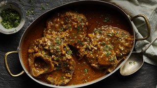 Ossobuco served in a metal casserole dish topped with parsley