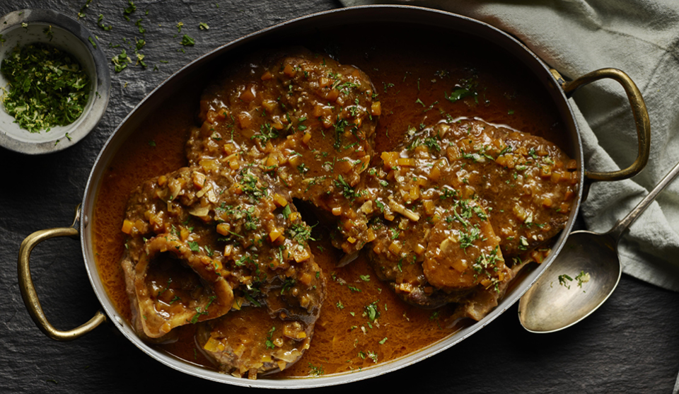 Ossobuco served in a metal casserole dish topped with parsley