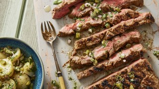 Griddled Miso Beef served sliced on a white board next to a fresh potato salad