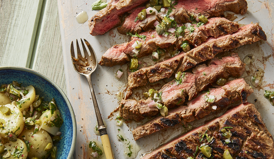 Griddled Miso Beef served sliced on a white board next to a fresh potato salad