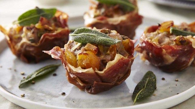 Parma Ham Stuffing Cups served on a grey plate, with sage leaves and cracked black pepper