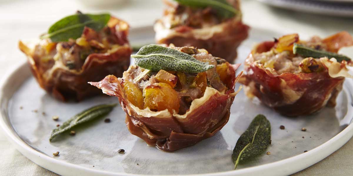 Parma Ham Stuffing Cups served on a grey plate, with sage leaves and cracked black pepper