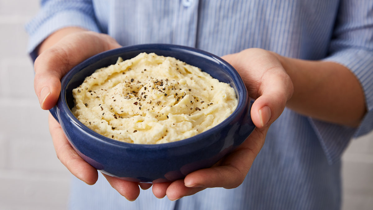 Perfect Parsnip Puree served in a blue bowl with cracked black pepper on top