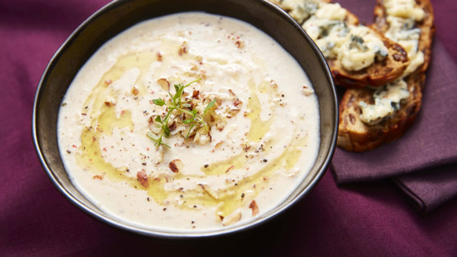 Parsnip and Hazelnut Soup with Blue Cheese Toasts served in a black bowl on a purple tablecloth