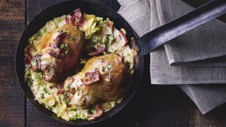 Partridge with cider and savoy cabbage served in a metal pan on top of a grey cloth