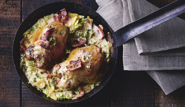 Partridge with cider and savoy cabbage served in a metal pan on top of a grey cloth