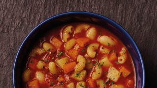 Pasta and Bean Soup served in a blue bowl topped with chopped parsley