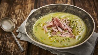 Hearty Pea and Ham Soup served in a grey dish on top of a grey tablecloth