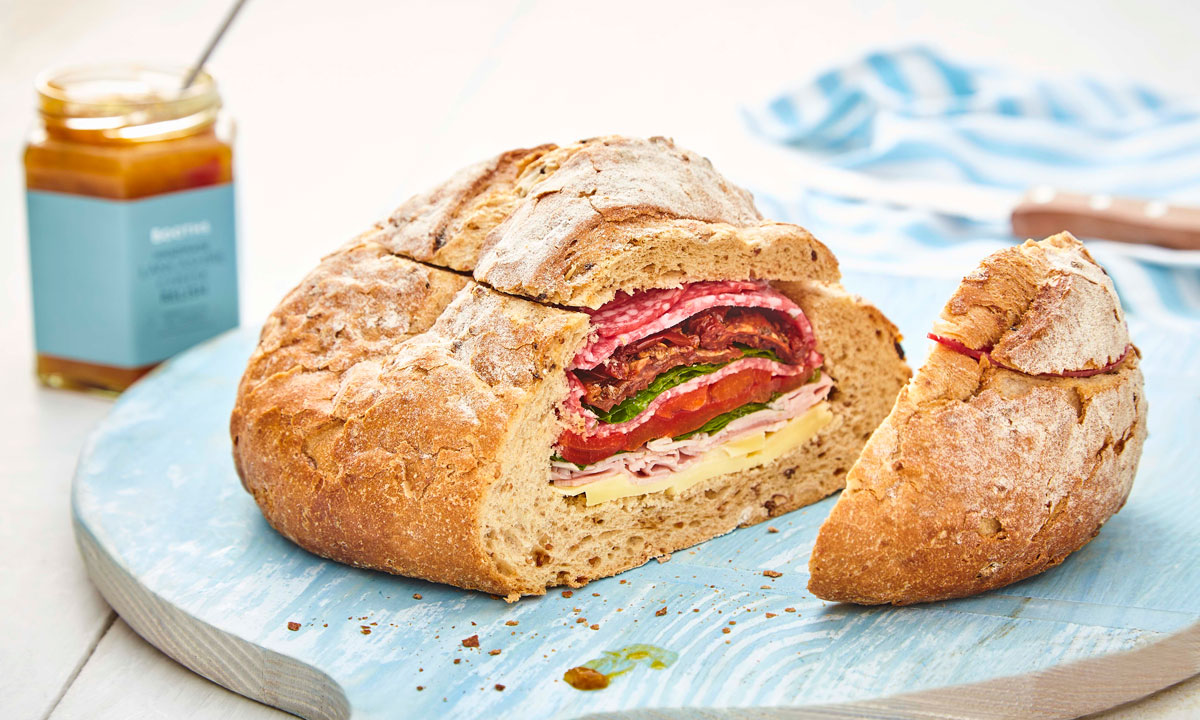 Picnic Loaf, sliced to see the filling, served on a blue board