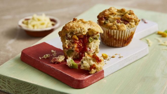 Pizza Muffins served on a wooden board with pieces removed to reveal the filling