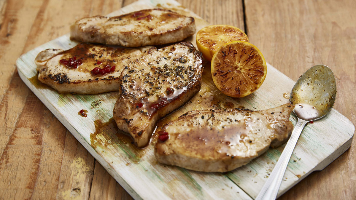 Pork Loin Chops and Spiced Clementine Sauce served on a wooden board with grilled clementines