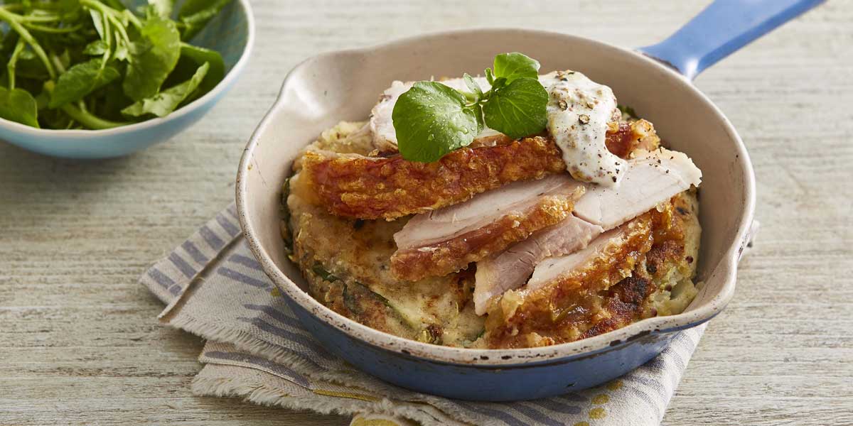 Potato and Apple Cakes with Leftover Roast Pork served in a casserole dish on top of a striped table cloth