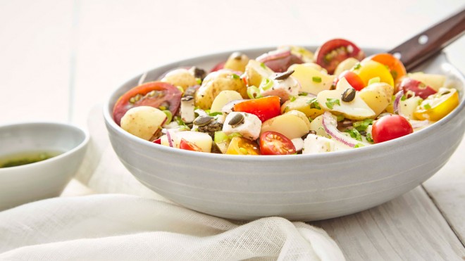 Gourmet Potato Salad, served in a grey bowl, topped with pumpkin seeds and parsley