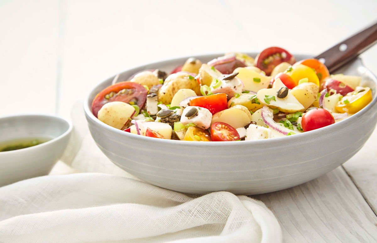 Gourmet Potato Salad, served in a grey bowl, topped with pumpkin seeds and parsley