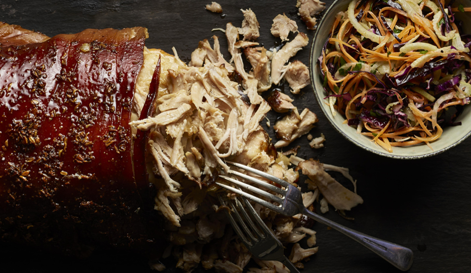 Pulled Pork which has been shredded by two forks next to a bowl of crunchy coleslaw