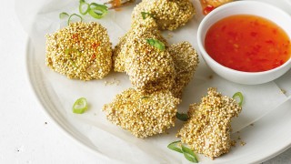 Crusty Quinoa Coated Chicken Nuggets, served on a white plate with slice spring onions and a small bowl of sweet chilli sauce