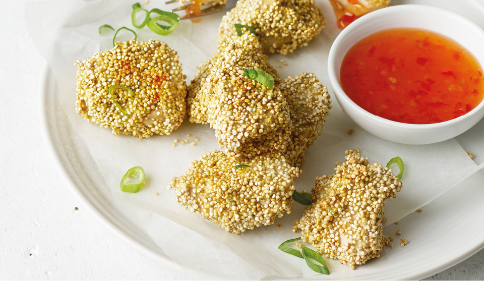 Crusty Quinoa Coated Chicken Nuggets, served on a white plate with slice spring onions and a small bowl of sweet chilli sauce