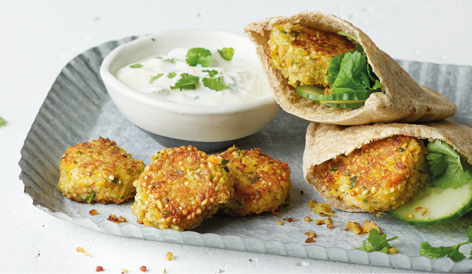 Spiced Quinoa Falafel served in pitta breads on a blue dish with a lemon and yoghurt sauce