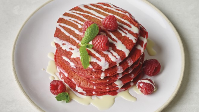 Red Velvet Pancakes with White Chocolate Sauce served on a white plate and topped with raspberries