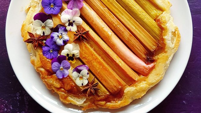 Autumn Spiced Rhubarb Tarte Tatin served on a white plate topped with edible flowers and star anise