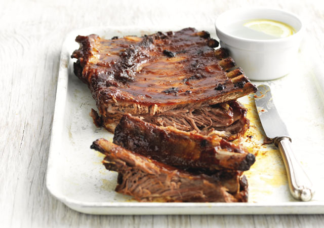 Spiced Barbeque Pork Ribsserved on a white plate with a couple of ribs pulled away