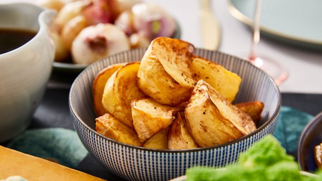 A bowl of roast potatoes in a blue and white bowl