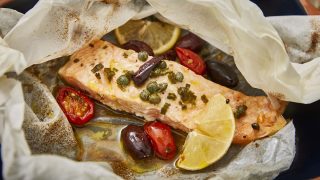 Salmon en Papillote served with olives, tomatoes and a wedge of lime