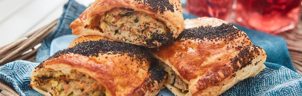 Sausage and Veg Picnic Rolls served on a blue plate on a wicker tray