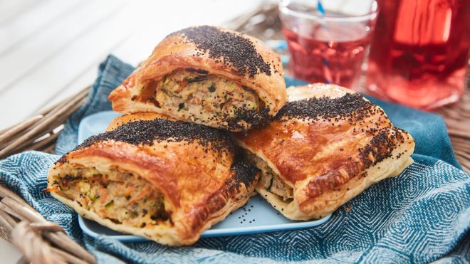 Sausage and Veg Picnic Rolls served on a blue plate on a wicker tray