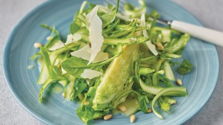 Shaved Asparagus and Pine Nut Salad served on a blue plate and topped with grated Parmesan