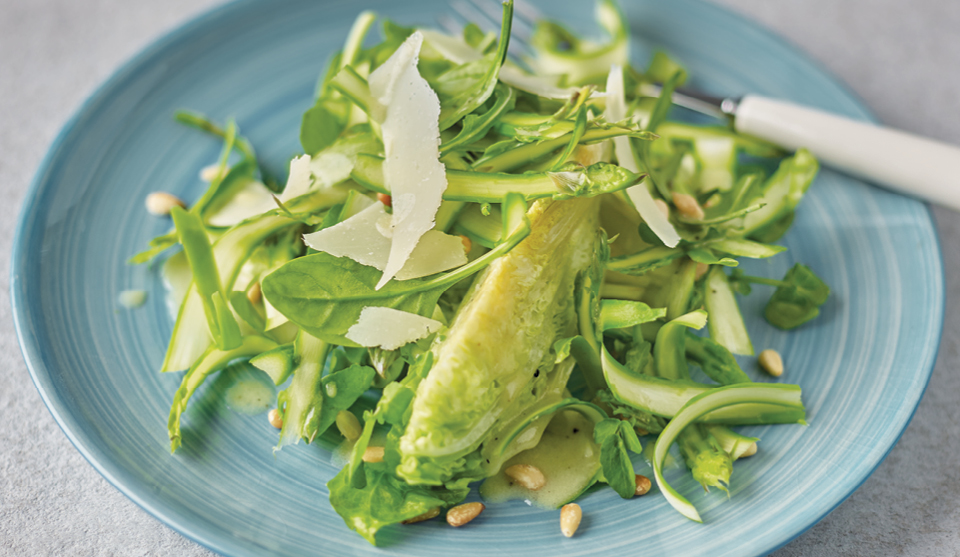 Shaved Asparagus and Pine Nut Salad served on a blue plate and topped with grated Parmesan