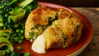Smoked Haddock and Cheddar Cheese Fishcake served on a red plate with vegetables, the fishcake has been cut into for the cheese to pour out