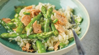 Asparagus and Hot Smoked Salmon Risotto served in a green bowl with a fork placed in the bowl